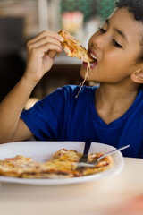 Happy african american kid eating pizza.