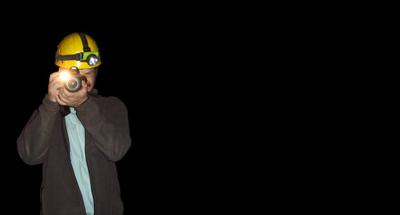 Man taking pictures towards the camera inside a cave.