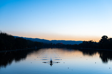 Lonely rowing boat sports in long canal training in calm sunset water with reflections and vibrant colors in Plovdiv, Bulgaria