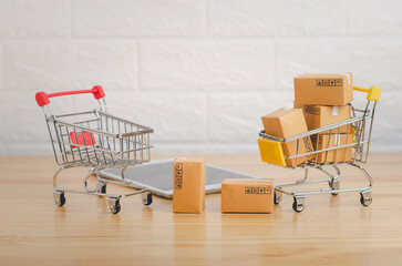 Brown paper boxs in shopping cart on wood table in office background.Easy shopping with finger tips for consumers.Online shopping and delivery service concept.