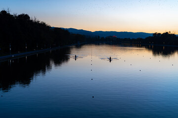 Kayaks racing in canal water reservoir for rowing sport practice on sunset vibrant background in Plovdiv, Bulgaria