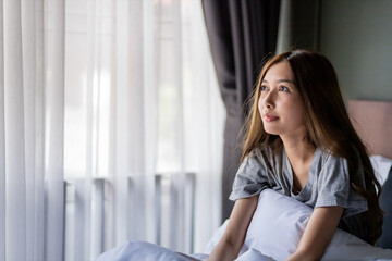 Beautiful long hair women sitting on the bed. while looking up for something.