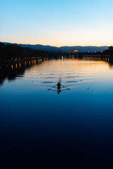 Lonely canoe kayak creating water ripples in calm sunset water canal sport rowing scenic sunset view in Plovdiv, Bulgaria