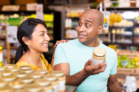 Portrait Of Emotional Latin American Man Choosing Foods In Grocery Store While Shopping With His Wife