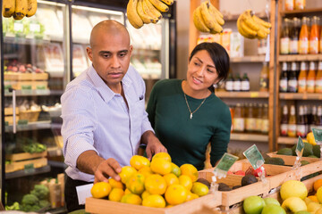 Married couple choosing fruits in grocery store