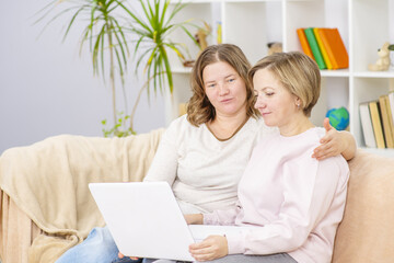 Happy lesbian couple embracing and using laptop at home.  Lesbian couple concept