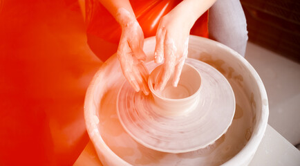 Female hands crafting a pottery cup on a potter's wheel. Handmade and crafting concept. Top horizontal view copyspace.
