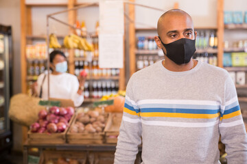Man in protective mask with basket at grocery store
