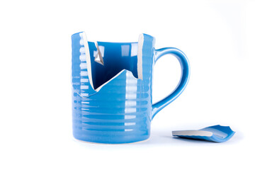 Broken blue mug with a shattered piece laying next to it