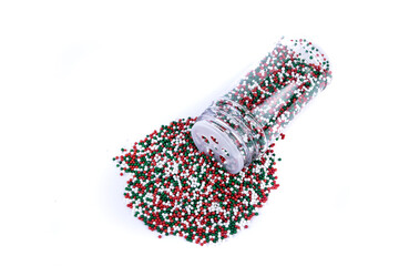 Red white and green sprinkles heaping amount spilled from a container with a shaker lid