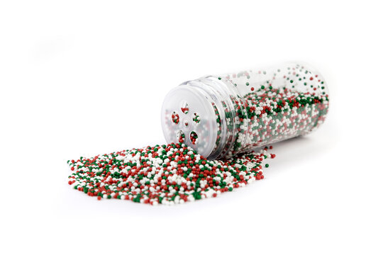 Red white and green sprinkles spilled from a container isolated over white background