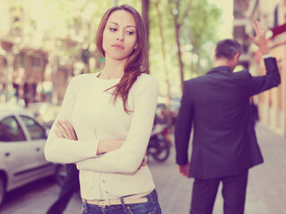 Fototapeta premium Offended girl on departing boyfriend background after quarrel outdoors