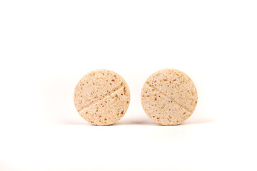 Two yellow and brown flecked chewable dog multivitamins standing next to each other isolated over white