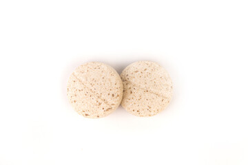 Two yellow and brown flecked chewable dog multivitamins top down view isolated over white