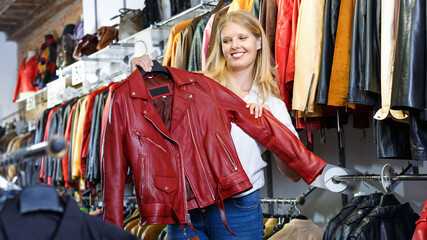 Smiling glad female customer satisfied with purchases in leather clothing boutique