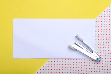 Stapler and empty white paper with a colored background