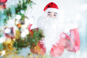 Asian man in Santa costume with OK sign gesture standing