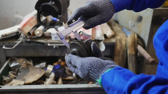 Hand close up of technician measuring engine part by vernier caliper
