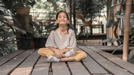 7 or 8 years old Asian school kid image.Girl happy and relax on her holidays in oriantal nature garden. Earth tone portait of Asian kid.