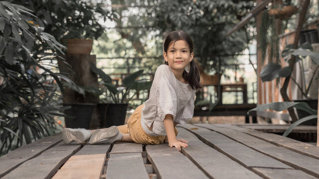 7 or 8 years old Asian school kid image.Girl happy and relax on her holidays in oriantal nature garden. Earth tone portait of Asian kid.