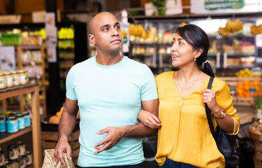 Casual latin american family couple doing shopping together in food department of supermarket