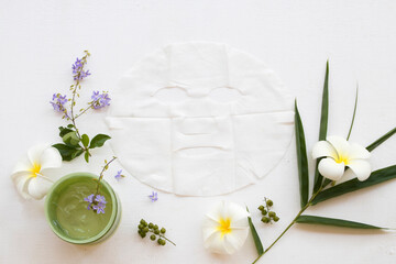 natural cosmetics herbal soothing gel and sheet mask aroma face mask from bamboo health care for skin face with bamboo leaf ,frangipani ,purple flower decoration flat lay style on background white 