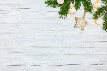 Fototapeta na wymiar festive winter white wooden background with christmas tree branches, star and holiday lights