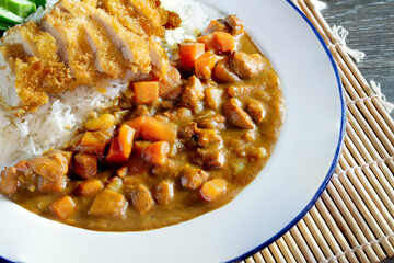 Japanese curry and fried pork Tonkatsu on rice in white dish on bamboo mat, Japanese food