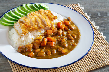 Japanese curry and fried pork Tonkatsu on rice in white dish on bamboo mat, Japanese food