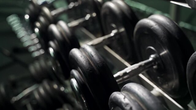 Rack with dumbbells in the gym. The movement of the camera along the rack with dumbbells.