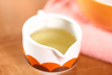 Sauce boat with vegetable oil. Making mayonnaise with a wooden spoon.