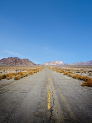 Abandoned rundown road, moon and distant mountains in remote west Nevada