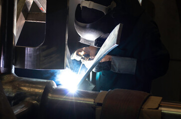 Metal workers use manual labor, Skilled welder, Factory workers making OT. Welder is welding the steel in the factory.