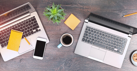 Working from home setup. Two laptops and tea coffee mugs on wooden rustic desk. remote working or...