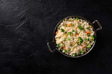 Vegan rice, stir fried, shot from the top on a black background with copyspace