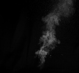 White vapour spray steam from air saturator. Smoke fragments on a black background.