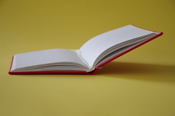 Open red notebook on yellow background