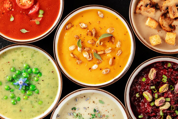 Vegan cream soup variety. Various vegetable soups, shot from the top on a black background