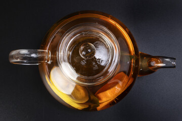 Liquid tea lemon orange slice green leaf cinnamon stick in transparent glass teacup saucer teapot...