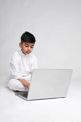 Cute indian boy using laptop over white background