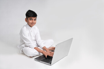 Cute indian boy using laptop over white background