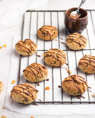 oatmeal cookies. Healthy and crunchy homemade dessert made of fresh grated carrot, raisins and rolled oats decorated with chocolate.  White background, orange biscuits. Top view, copy space.