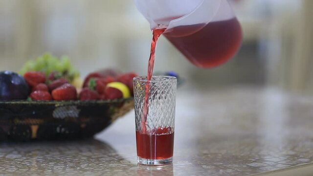 Pouring red beverage into a glass
