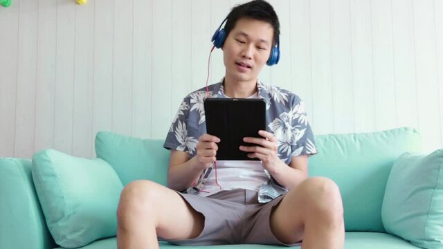 Portrait Young Asians listen to taplet music on the sofa in the living room.