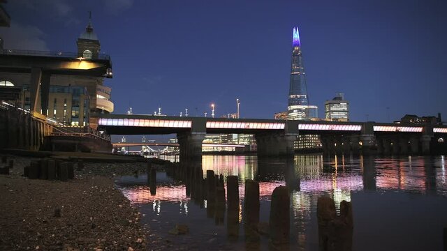 London skyline with lights at night on the River Thames beach at low tide looking at the Shard, shot in Coronavirus Covid-19 lockdown