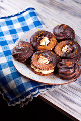 Chocolate covered marshmallow cookies on a plate on a blue and white napkin on wooden table