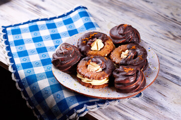 Chocolate covered marshmallow cookies on a plate on a blue and white napkin on wooden table