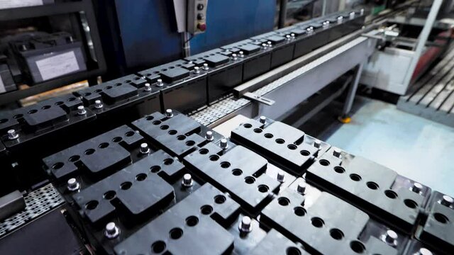 Automatic line for the assembly of car batteries. The black batteries move and collect on the conveyor belt.