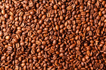 Background with roasted  coffee beans on the wooden table. Shot from above. Warm colors background with coffee beans.