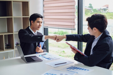Young asian businessman partners fist bump showing cooperation and success at work.